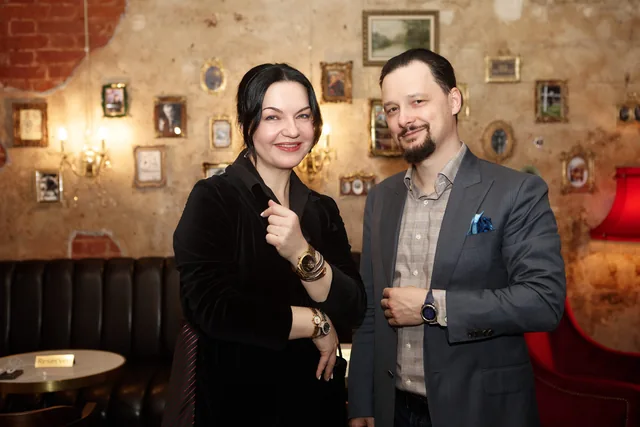 Участники вечера у стены с коллекцией портретов
